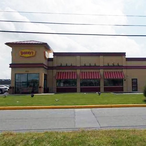 An exterior view of a Denny's restaurant with red striped awnings