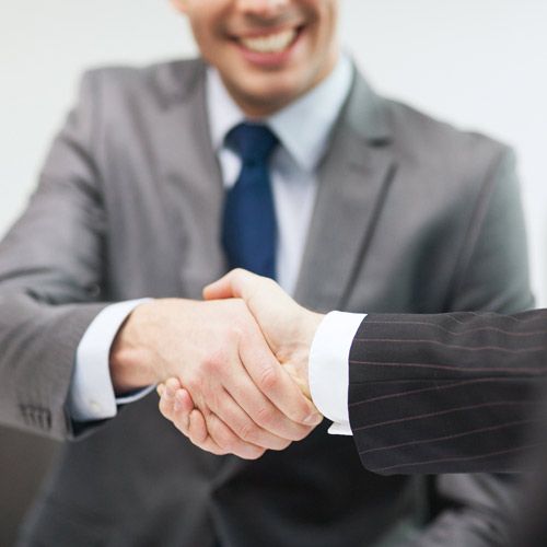 close up of two business men wearing suits shaking hands